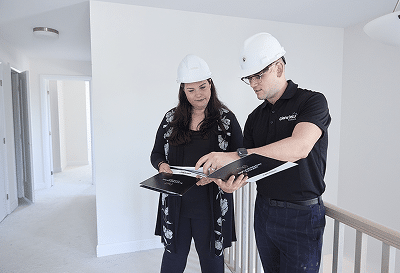 two people with hard hats on reviewing a folder